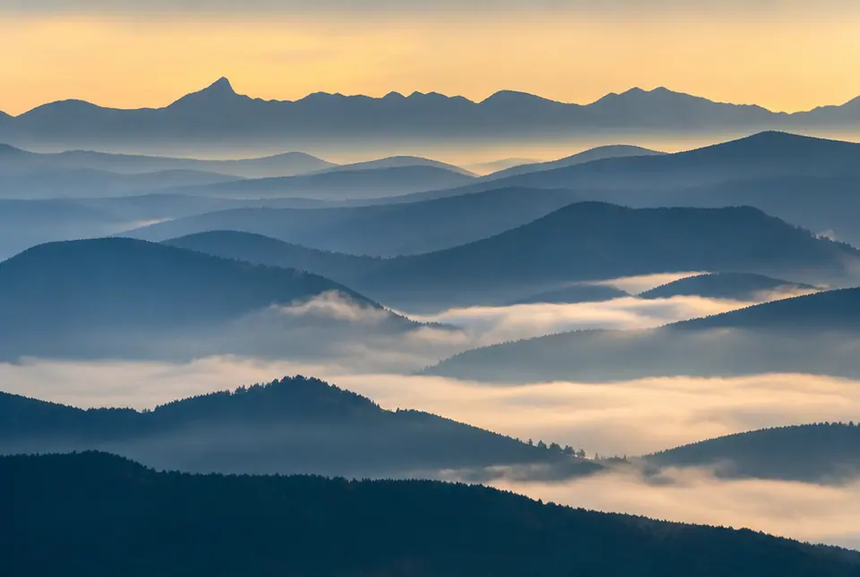 Layered mountain ridges at dawn with low fog in the valleys