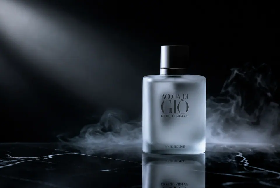 Frosted glass perfume bottle on polished black marble with dramatic side light and mist